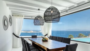 Comedor con una mesa de madera y sillas negras, con vista a un paisaje marino.