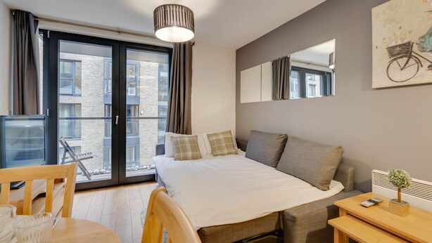 Ein modernes Hotelzimmer mit einem großen Bett, einem Esstisch und einem Balkon mit Blick auf die Stadt.
