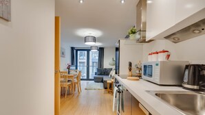 Eine moderne Küche mit Mikrowelle, Wasserkocher und Spüle. Ein Essbereich mit Tisch und Stühlen ist vorhanden.