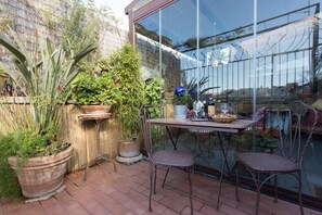 A patio with potted plants, a table, and two chairs.