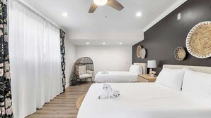 Una camera d'albergo con due letti, una ventola a soffitto, una lampada a parete e un elemento decorativo al muro.
