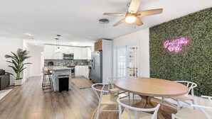 Una cucina moderna con mobili bianchi, un'isola centrale e un neon sulla parete.