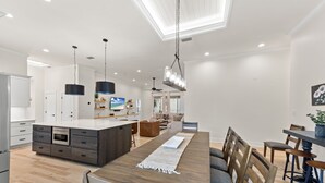 Une cuisine moderne dotée d’un îlot central, d’une table à manger en bois et de tabourets de bar.