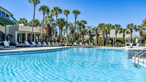 Une piscine d’un bleu éclatant, avec des chaises longues et des palmiers.