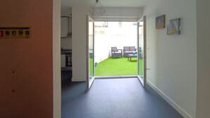 Een gang die uitkomt op een balkon met een groen gazon en terrasmeubels.