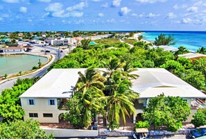 A coastal resort with a large building surrounded by lush greenery and a clear view of the ocean. - Few steps from the ocean, Two bedrooms apartment-CORAL GARDENS-Grand Turk Island (Turks Islands)