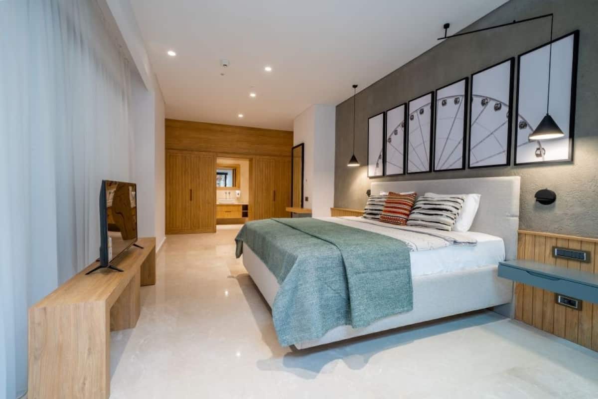 Un dormitorio moderno con una cama grande, un armario de madera y un televisor sobre un mueble de madera.