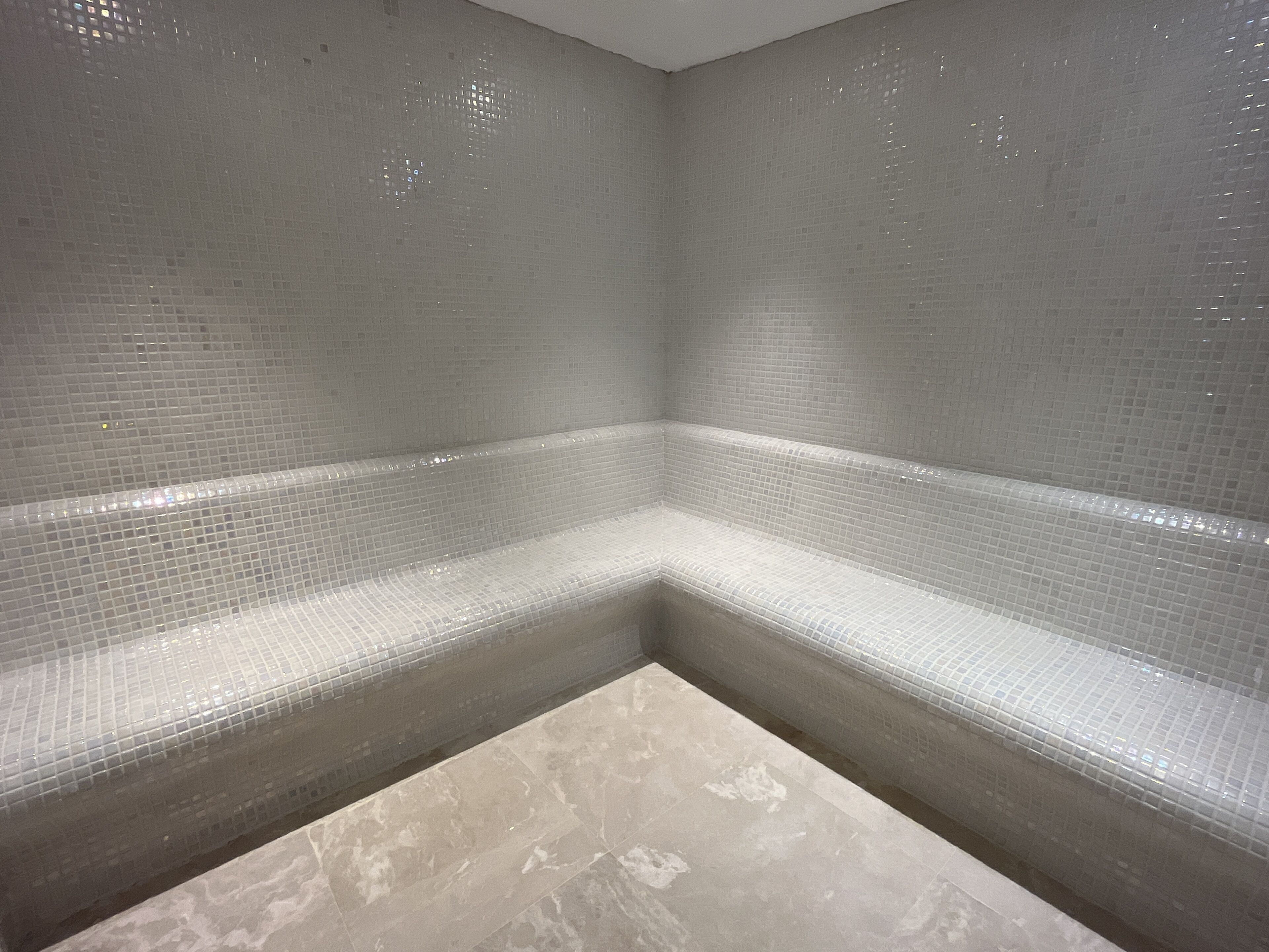 A corner of a room with tiled walls and a marble floor.