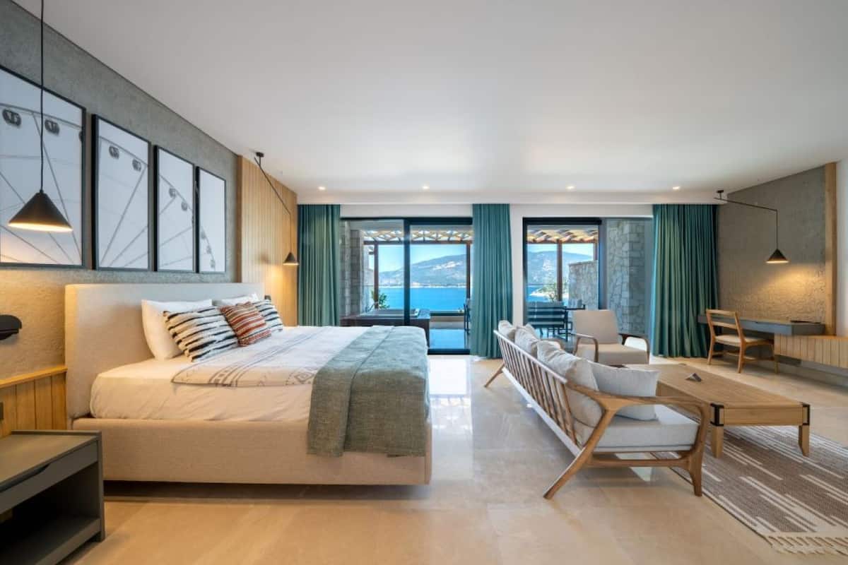 Un dormitorio moderno con una cama grande, un escritorio y vista al mar.