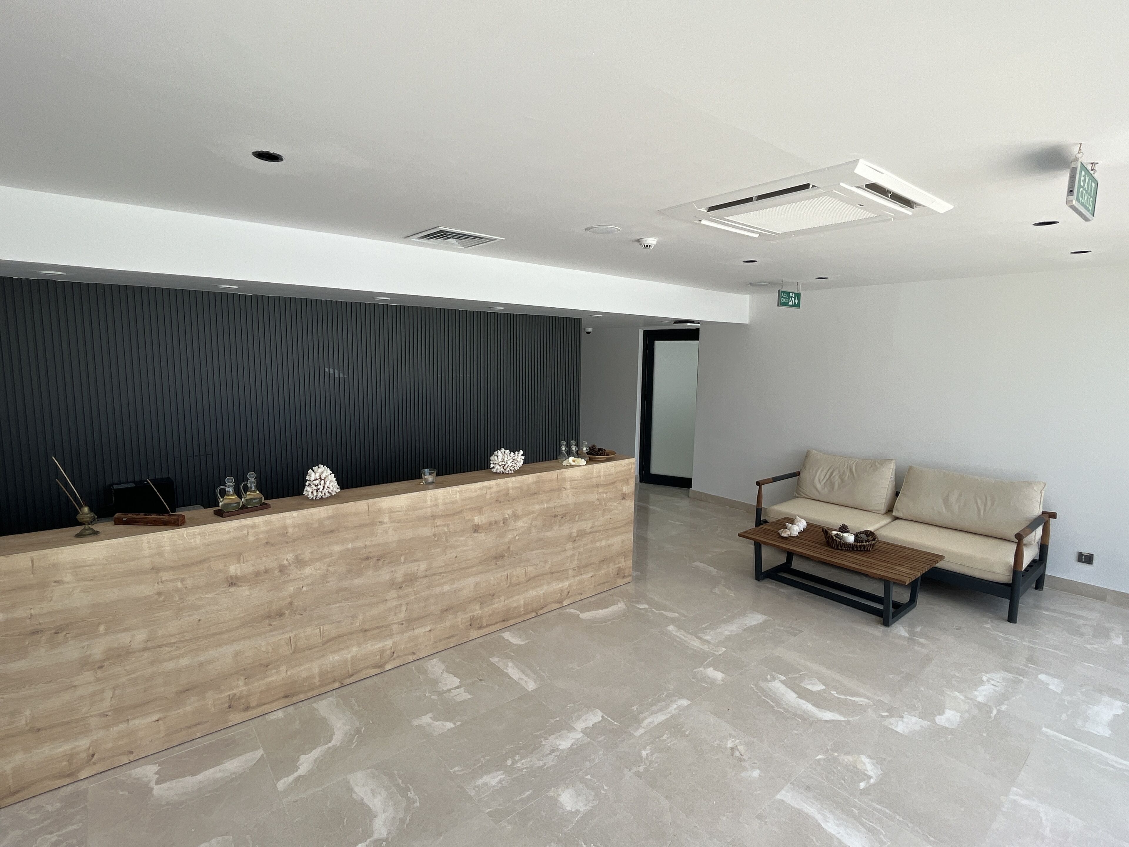 A reception area with a wooden desk, a sofa, and a tiled floor.