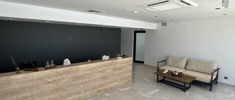 A reception area with a wooden desk, a sofa, and a tiled floor.