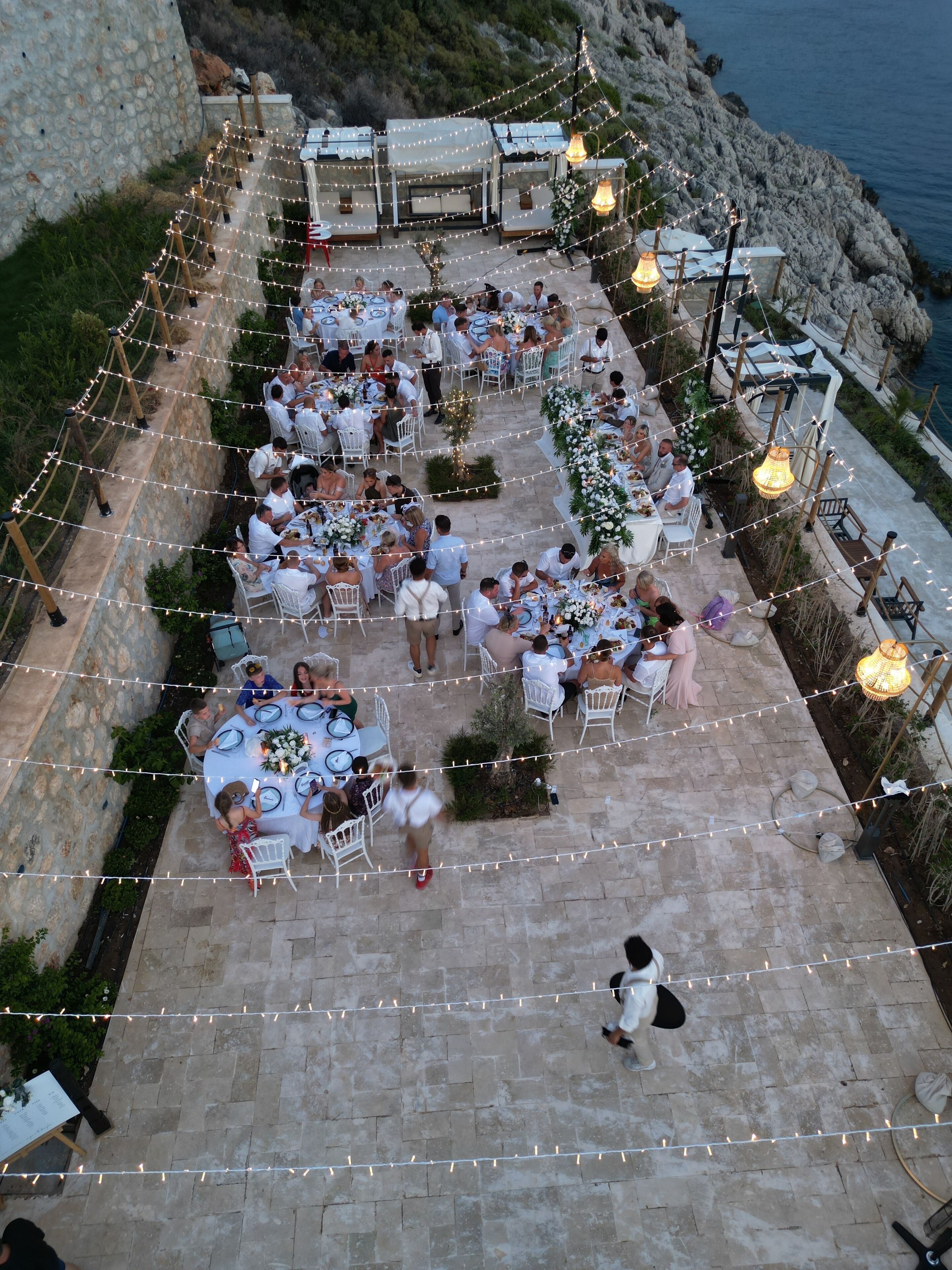 Un área de comedor al aire libre con guirnaldas de luces y mesas preparadas para los huéspedes.