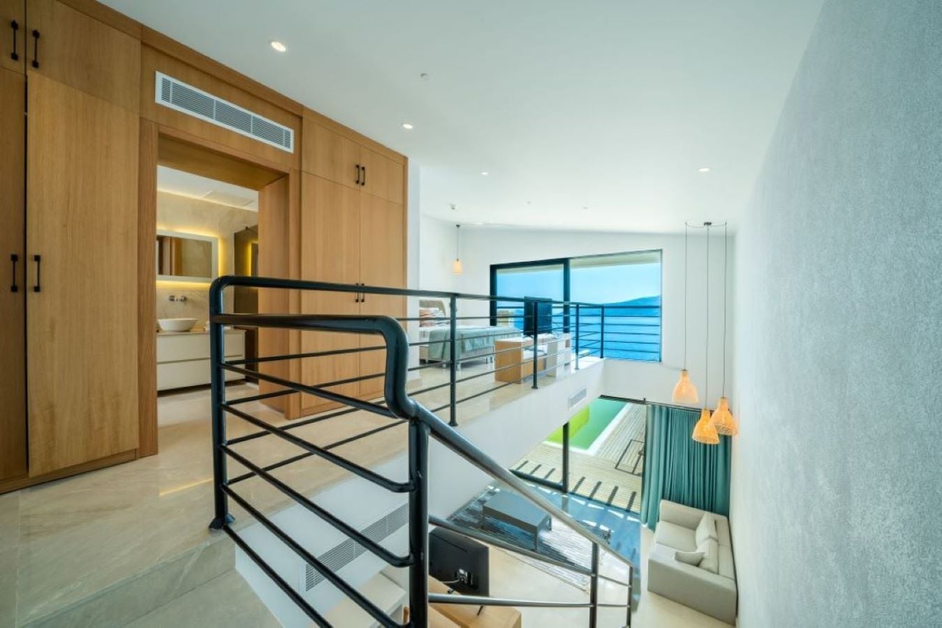 A modern interior with a kitchen, dining area, and a balcony with a view of the sea.