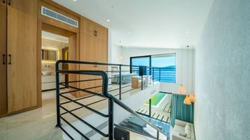 A modern interior with a kitchen, dining area, and a balcony with a view of the sea.