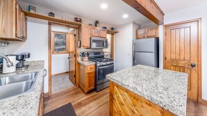 Eine Küche mit Holzschränken, Granit-Arbeitsplatten, Edelstahlgeräten und einem Holzbalken an der Decke.