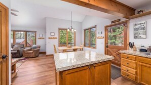 Eine geräumige Küche mit Granit Arbeitsplatten, Holzschränken und einer großen Kochinsel. Es gibt einen Essbereich mit Tisch und Stühlen sowie ein Wohnzimmer mit Sofa und Kamin.