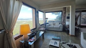 A living room with a sofa, a coffee table, a TV, and a view of the countryside. - Villa Vista, from the terrace a stunning view to  Costa Smeralda and the Islands (Sardegna)