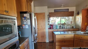 A kitchen with wooden cabinets, a stainless steel refrigerator, a microwave, a stove, and a window with a view of the outdoors. - Green Valley, Gorgeous Mtn Views, Private pool (Green Valley)