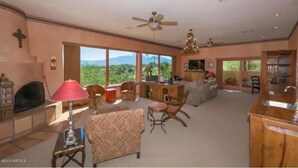 A spacious living room with a fireplace, comfortable seating, and large windows offering a mountain view. - Green Valley, Gorgeous Mtn Views, Private pool (Green Valley)