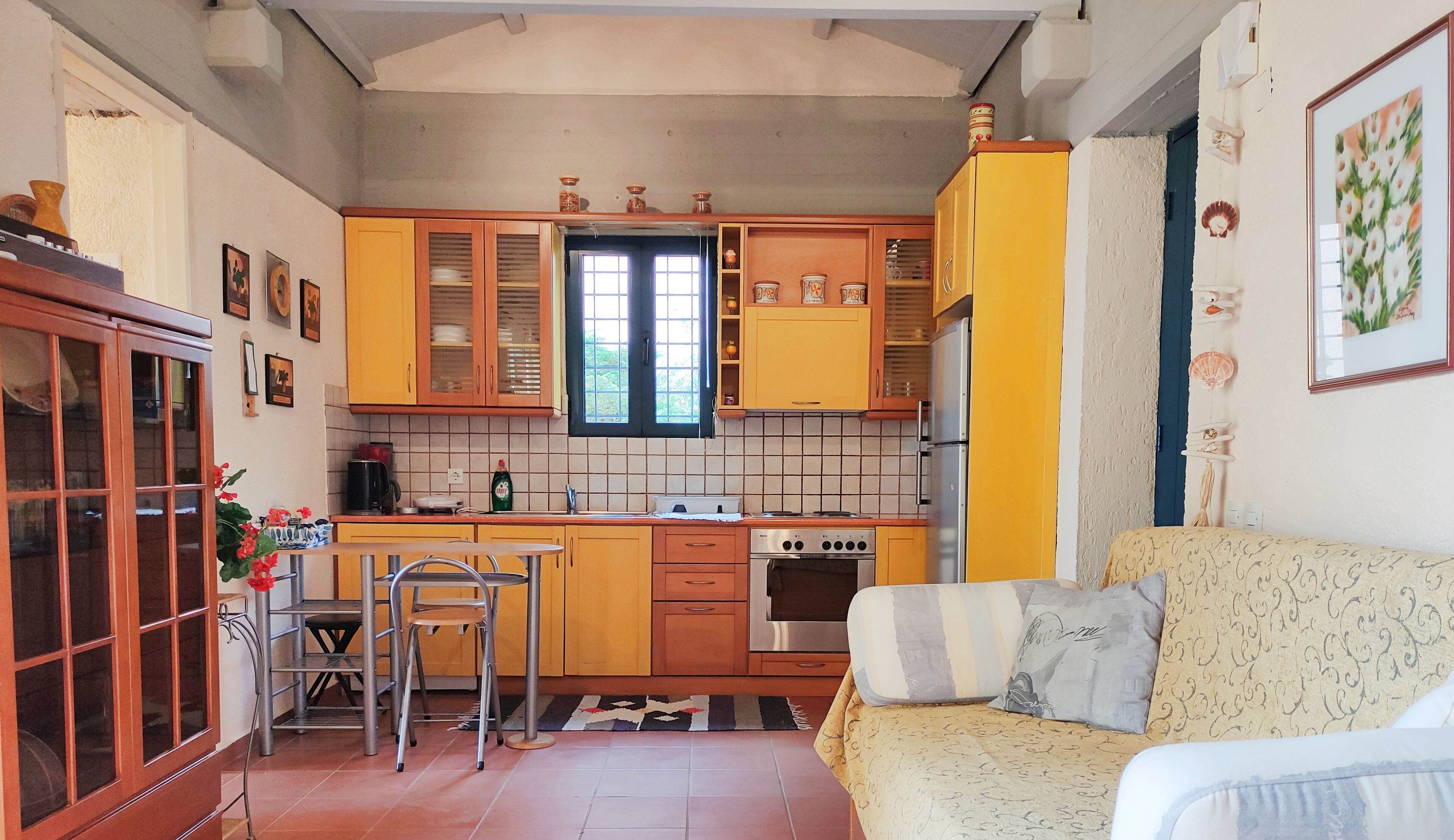 A compact kitchen with yellow cabinets, a stove, and a dining area with a table and chairs.