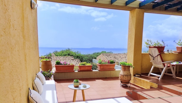 A covered patio with a white sofa, a small round table, and potted plants. - Mira El Mar by Corfuescapes (Corfu)