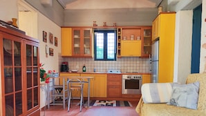 A compact kitchen with wooden cabinets, a gas stove, and a refrigerator. - Mira El Mar by Corfuescapes (Corfu)