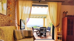 A cozy living room with a TV, a sofa, and a dining area with chairs and a table. - Mira El Mar by Corfuescapes (Corfu)