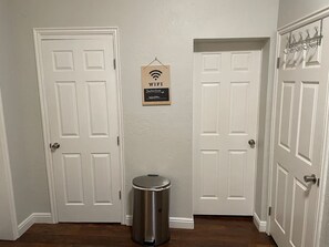 A hallway with two white doors, a trash can, and a WiFi sign.
