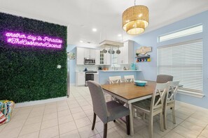 Una cocina moderna con armarios blancos, una mesa de comedor de madera y un letrero de neón en la pared.
