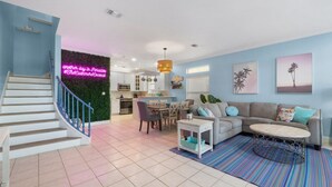 A modern living room with a staircase, a dining area, and a kitchen. - BEACH HOUSE! Walk to Private Beach Gate, Pickleball, Rent Golf Cart, Heated Pool (Destin)
