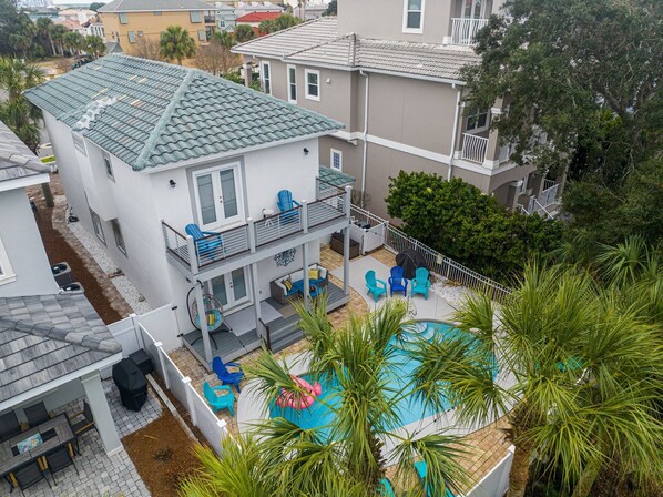 Una casa de dos pisos con balcón, piscina y mobiliario de exterior.