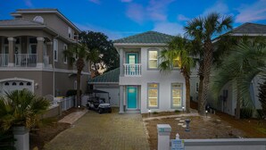 A two-story house with a blue door, a garage, and a golf cart parked in front. - BEACH HOUSE! Walk to Private Beach Gate, Pickleball, Rent Golf Cart, Heated Pool (Destin)