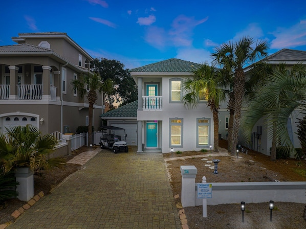 A two-story house with a blue door, a garage, and a golf cart parked in front.