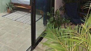 Een kamer met een bed, een schuifdeur en potplanten.