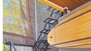 Een trap die leidt naar een houten terras, met een surfboard tegen de trap aan.