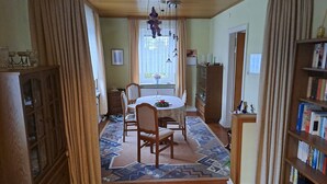 En matplats med ett runt bord, stolar, en mönstrad matta och en bokhylla.