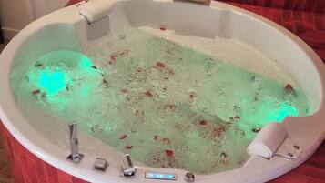 A hot tub with a control panel and a red-tiled wall.