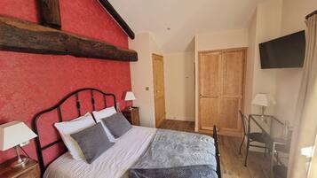 Une chambre à coucher avec un lit, des tables de chevet, une armoire en bois, une télévision et une chaise.