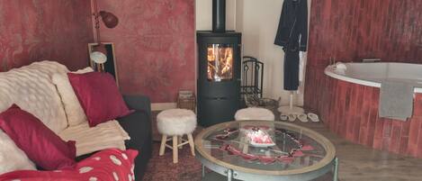A cozy room with a fireplace, a sofa, a round table with items, and a bathtub.