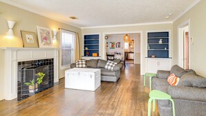 Een woonkamer met een open haard, een bank, een salontafel en een boekenkast.