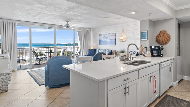 A modern kitchen with a large island, white cabinetry, and a view of the ocean.