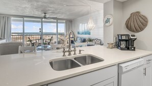 A modern kitchen with a large island, double sink, and a coffee station.