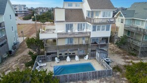 Un immeuble résidentiel à plusieurs étages doté d’une piscine dans le jardin, de chaises longues et d’un espace clôturé.