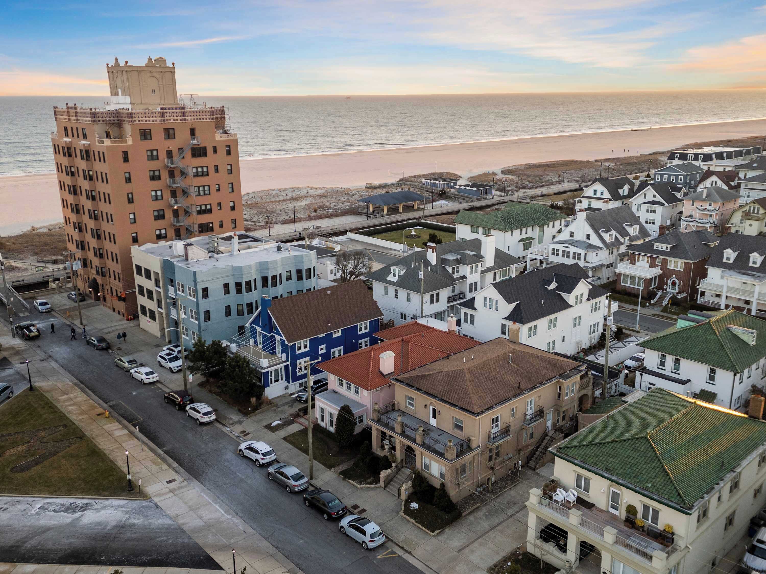 A coastal town with a mix of residential buildings, including a prominent red building and several white houses with green roofs.