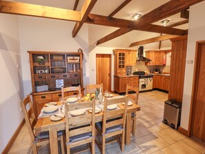 Une table de salle à manger en bois, mise avec des assiettes, des verres et un saladier de fruits.