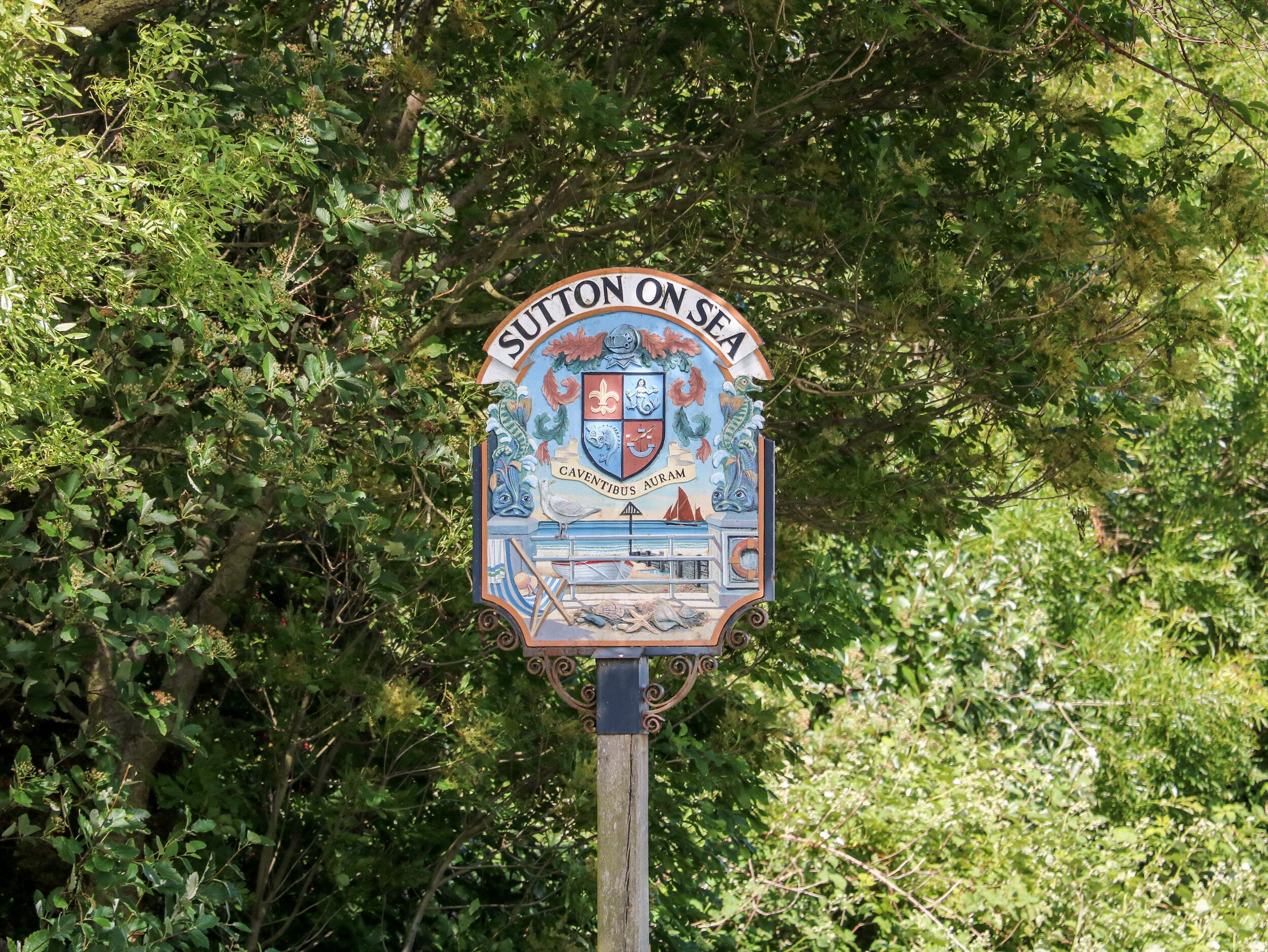 A sign with a coat of arms and the text "Sutton on Sea".