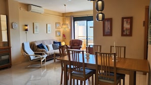 Een woonkamer met een bank, stoelen, een eettafel en kunstwerken aan de wanden.