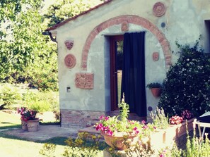 A small building with a brick archway and a door, surrounded by potted plants and flowers. - Vallacchi b&b Authentic Acient Tuscany CountryHouse, family welcome (Toscana)
