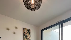 Un soggiorno moderno con un divano verde, un tavolino in legno con oggetti decorativi, un tappeto colorato e un'ampia finestra che si affaccia su un'area salotto esterna.