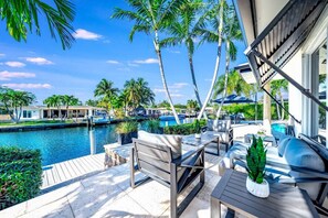 A poolside area with outdoor seating, a view of the water, and palm trees. - Heated Pool! WaterFront Home! 1 Mile To Beach! (Pompano Beach)